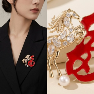 Détail d'une broche cheval doré avec caractère Fu rouge, cristaux et perle élégante