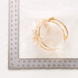 Vista dettagliata del bracciale rigido smaltato dorato con fiori e righello di misura