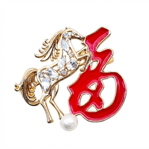 Détail de la broche cheval dorée avec caractère Fu rouge, cristaux et perle blanche