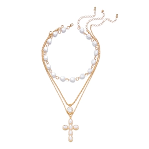 Détail d'un ensemble de colliers superposés avec perles baroques et grand pendentif croix