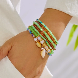 Detail of bohemian multilayer beaded bracelet set with natural shell pendant on wrist