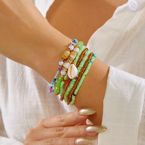 Detail of bohemian layered colorful seed bead bracelets with natural shell charms