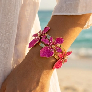 Bracciale rigido floreale dorato in smalto con fiori rosa su sfondo di spiaggia soleggiata