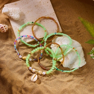 Bohemian multi-layer colorful beaded bracelets with shell pendant on beach sand background