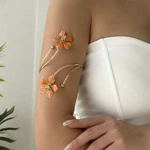 Détail d'un bracelet de bras doré élégant avec des fleurs en émail orange porté