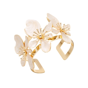 Vista dettagliata di un bracciale rigido dorato con fiori in smalto bianco e decorazioni
