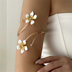 Détail d'un bracelet de bras doré élégant avec fleurs en émail blanc et design enveloppant