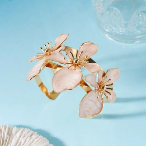 Dettaglio di fiori in smalto rosa e farfalla dorata su un ampio bracciale aperto