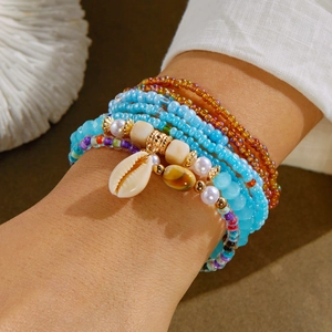 Detail of bohemian multilayered colorful bead bracelet with shell charm and pearl on wrist
