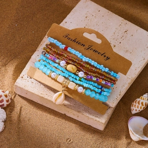 Detail of bohemian multilayer bead bracelets with shell pendant on a beach setting
