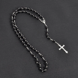 Elegant black rosary necklace with a silver cross pendant over a dark grey background