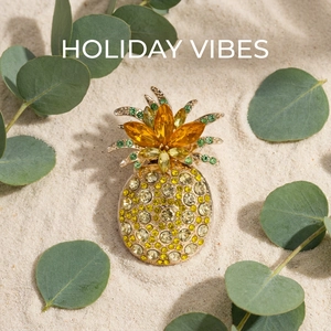 Detail of luxury pineapple brooch with yellow crystals on a white sand background