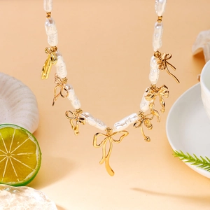 Détail du collier de perles baroques avec pendentifs en forme de nœud doré