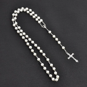 Close-up of pearl bead chain necklace with textured silver cross pendant on grey background