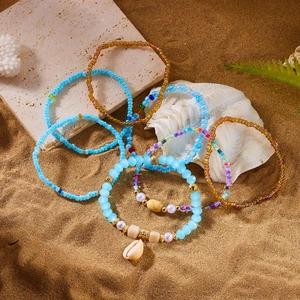Detail of bohemian beaded bracelets with blue beads and shell charms on sandy background