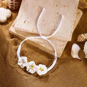 Detailansicht der weißen Plumeria-Blüten am geflochtenen Armband mit kleinen Strasssteinen