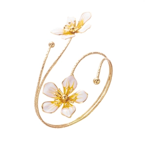 Détail macro de fleurs en émail blanc sur un bracelet jonc doré avec texture tressée fine
