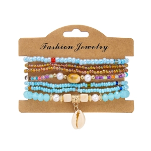 Close-up of bohemian beaded bracelet set featuring shells and pearls on a paper card