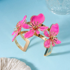 Dettaglio del bracciale dorato con fiori 3D in smalto rosa e trama marmorizzata