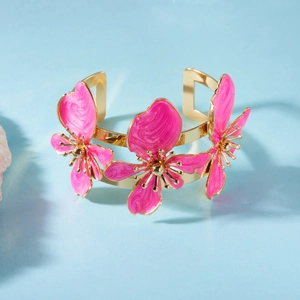 Dettaglio delle decorazioni floreali in smalto rosa sul bracciale aperto dorato