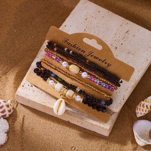 Detail of bohemian multilayer bead bracelets with shell pendant on a beach stone