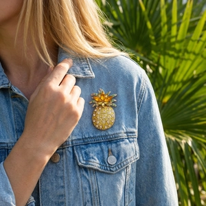 Detail of a luxury pineapple brooch with colorful crystals on a denim jacket