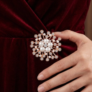 Broche flocon de neige élégante en or rose avec perles et cristaux sur velours rouge