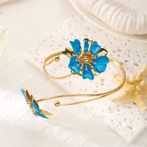 Détail macro des fleurs en émail bleu et courbes métalliques dorées sur le bracelet