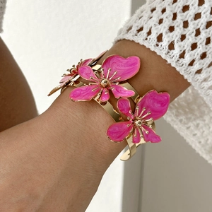 Dettaglio di fiori in smalto rosa e trama dorata su questo ampio bracciale rigido