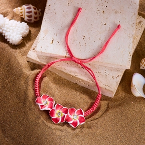 Detailansicht der roten Frangipani-Blüten mit Kristallen auf gewebtem Strand-Armband für Damen