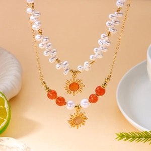 Détail d'un collier à deux rangs avec perles baroques et pendentifs soleil dorés