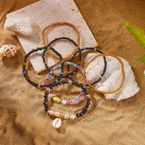 Macro shot of Bohemian multi-layer beaded bracelets with a shell charm on golden beach sand