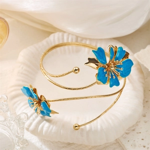 Détail de fleurs en émail bleu sur un bracelet doré ouvert avec design floral élégant