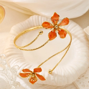 Détail macro d'un bracelet ouvert doré avec deux fleurs orange en émail 3D