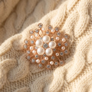 Élégante broche flocon de neige en or rose avec perles et cristaux sur pull en tricot