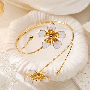 Vue macro de fleurs élégantes en émail blanc sur un bracelet doré ouvert sur plateau