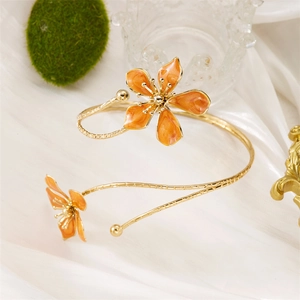 Gros plan détaillé d'un bracelet doré avec fleurs en émail orange sur fond de soie