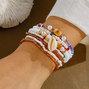 Detail of layered bohemian shell bracelet with colorful beads on a sunlit beach