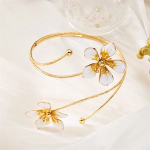 Détail d'un élégant bracelet fleur en émail doré sur fond de tissu de soie blanche