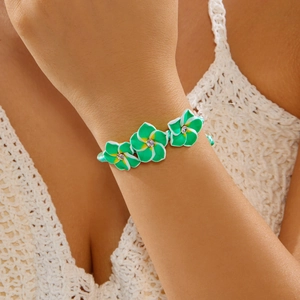 Detail von gewebtem Armband mit grün-weißen Tonblumen und Kristallzentren