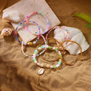 Detail of bohemian beach bracelets set with sea shells and colorful beads on sand