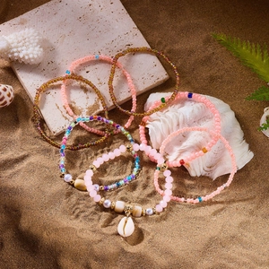 Detail of bohemian beaded bracelets with white natural shell pendant on a beach setting
