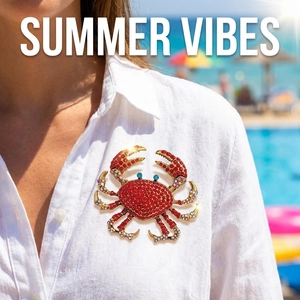 Detailed close-up of a luxury crab brooch with red crystals worn on a summer dress