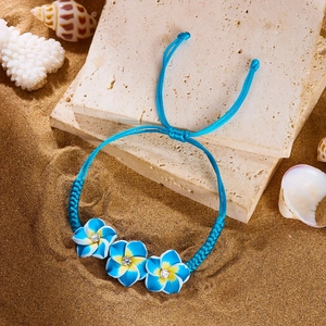 Makroaufnahme von blauem Plumeria-Blumenarmband auf Strandsand mit Muscheln
