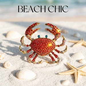 Luxury crab brooch with red rhinestones and blue eye detail on beach sand background
