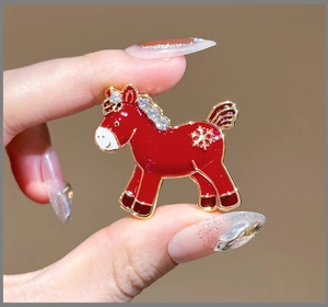 Close-up of a festive red horse brooch with gold trim and sparkling rhinestones