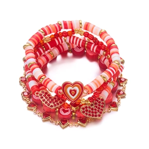 Detail van rode polymeerklei kralenarmbandset met gouden hartvormige bedeltjes en accenten