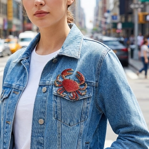 Luxurious gold alloy crab brooch with vibrant red rhinestones on denim jacket