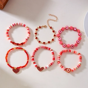Detail van 6 rode en roze polymeerklei armbanden met goudkleurige hartjes en bloemkralen