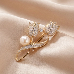 Détail de la broche tulipe dorée avec cristaux scintillants et une grande perle blanche